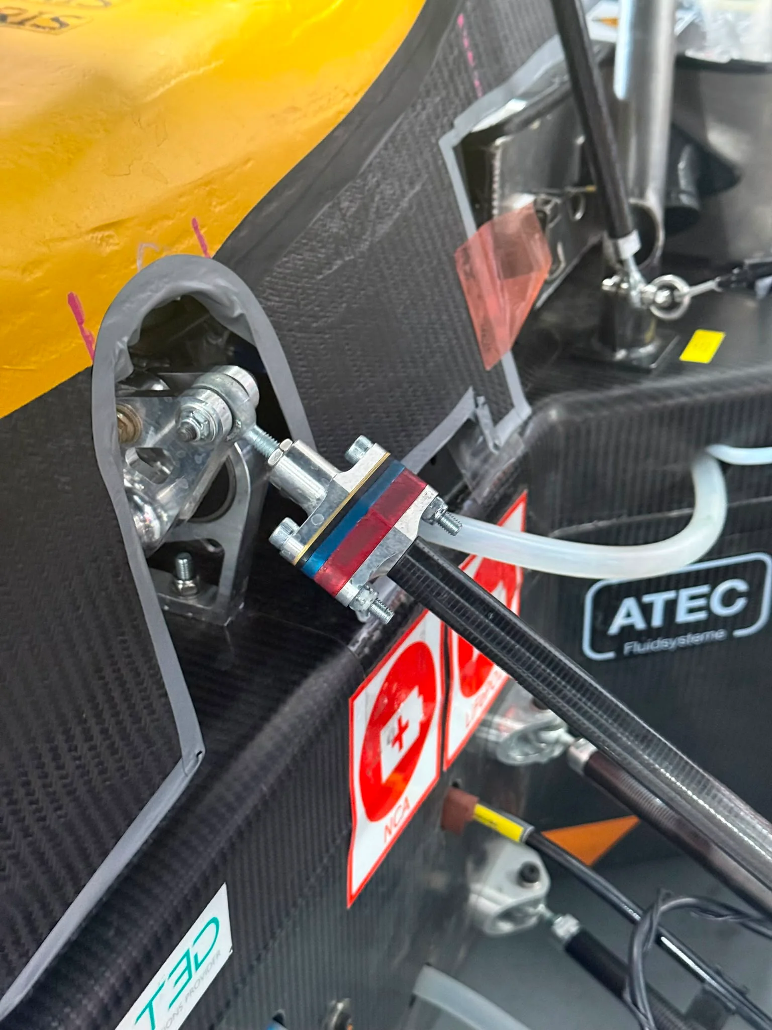The shim clamp fitted on the car, bolts accessible with the pushrod in place