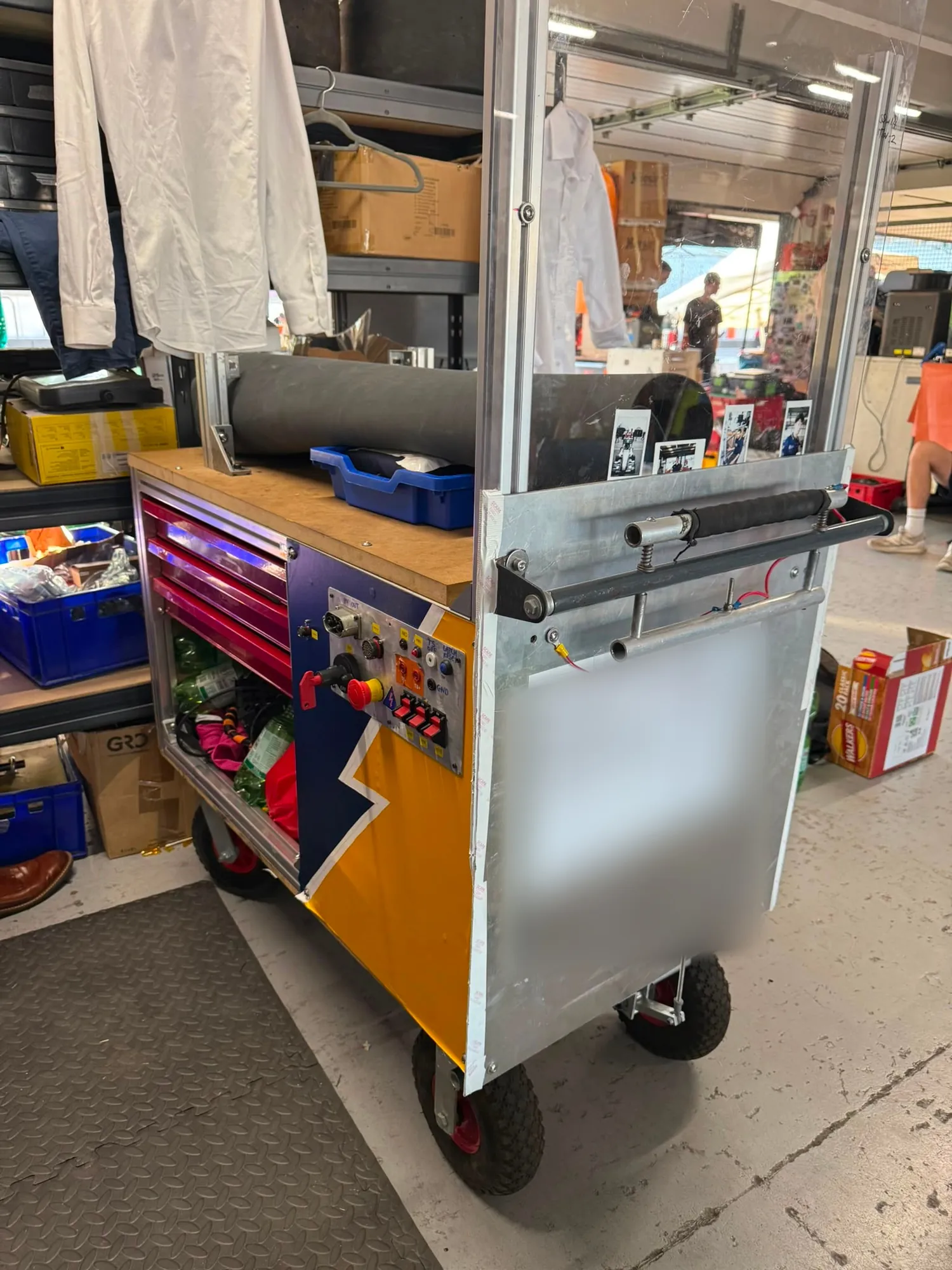 The finished trolley: extrusion frame, tool drawers under a timber worktop, control panel and emergency stop on the near face, pneumatic wheels
